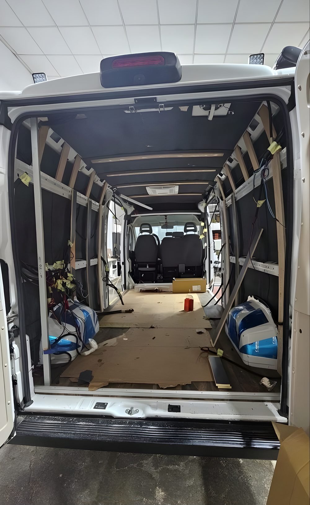 Furgón alto abierto por detrás en pleno aislamiento: paredes forradas en negro y listones de madera