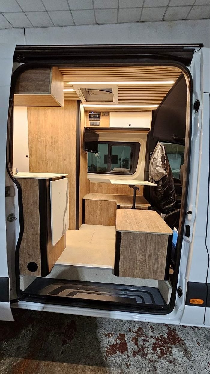 Camper con las puertas traseras abiertas y mobiliario de madera a medida