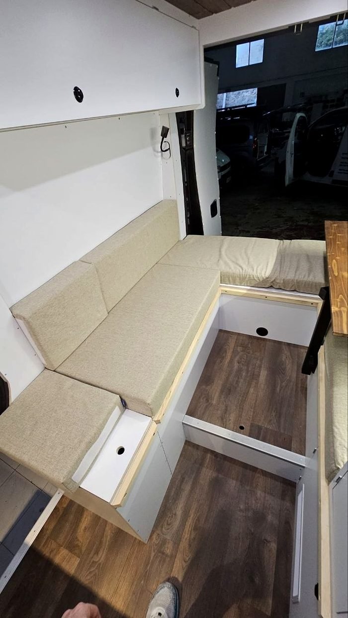 Banco corrido tapizado y suelo de madera en el interior de una camper