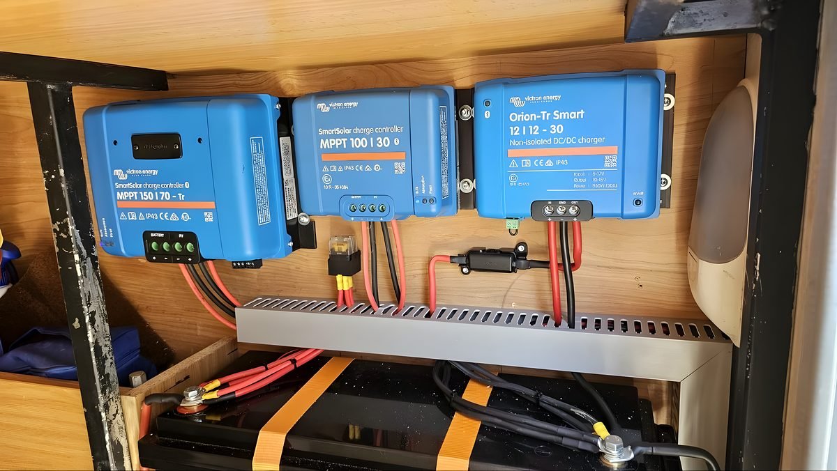 Reguladores y cargadores Victron azules instalados sobre la batería auxiliar de una camper